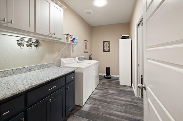 clothes washing area featuring cabinets, dark hardwood / wood-style floors, and washer and clothes dryer