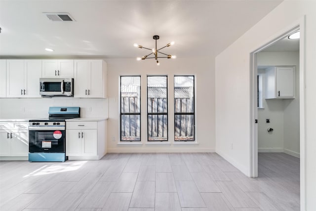 kitchen with backsplash, white cabinetry, a notable chandelier, and appliances with stainless steel finishes