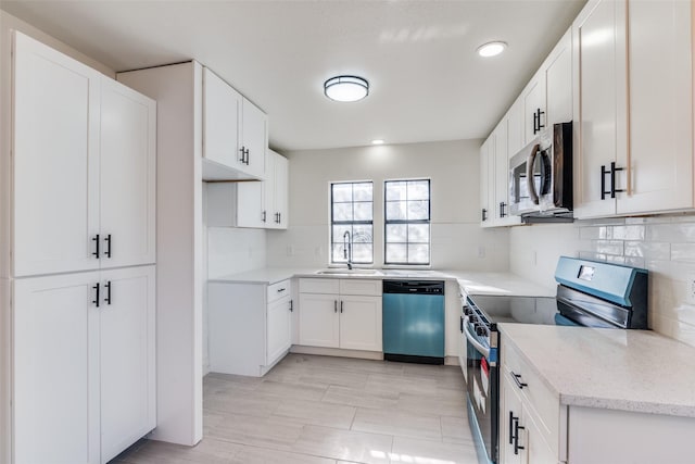 kitchen featuring appliances with stainless steel finishes, backsplash, light stone counters, sink, and white cabinets