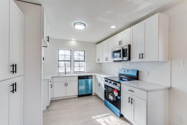 kitchen with tasteful backsplash, sink, white cabinets, and appliances with stainless steel finishes