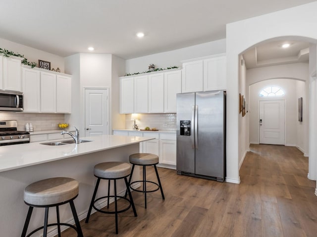 kitchen featuring sink, dark hardwood / wood-style flooring, a breakfast bar, white cabinets, and appliances with stainless steel finishes