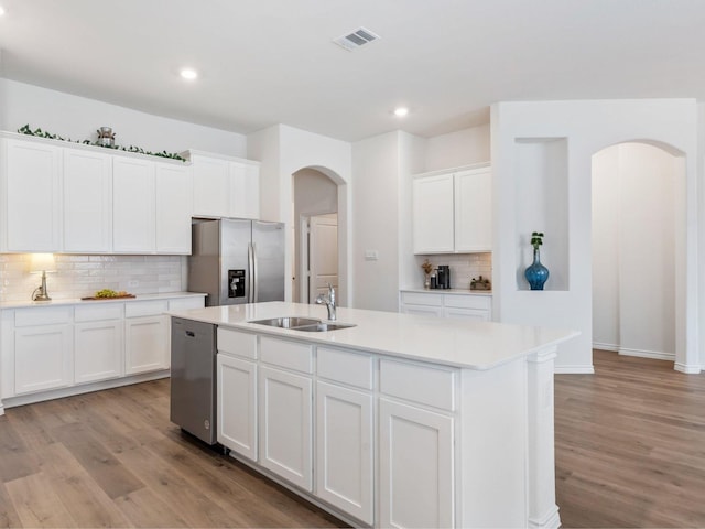 kitchen with white cabinetry, sink, stainless steel appliances, light hardwood / wood-style flooring, and an island with sink