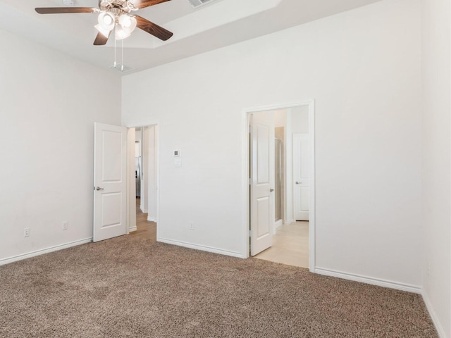 unfurnished bedroom featuring light carpet, ceiling fan, and a high ceiling