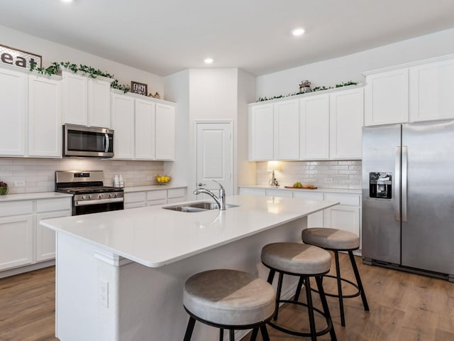 kitchen with a kitchen island with sink, white cabinets, and stainless steel appliances