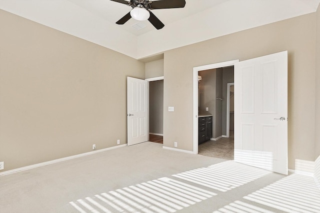 unfurnished bedroom with ensuite bathroom, ceiling fan, and light carpet