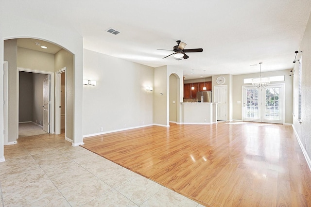 unfurnished living room featuring ceiling fan with notable chandelier and light hardwood / wood-style floors