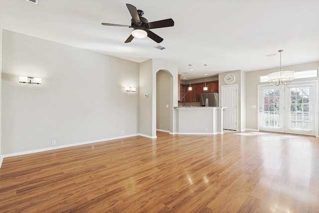 unfurnished living room featuring ceiling fan with notable chandelier and light wood-type flooring