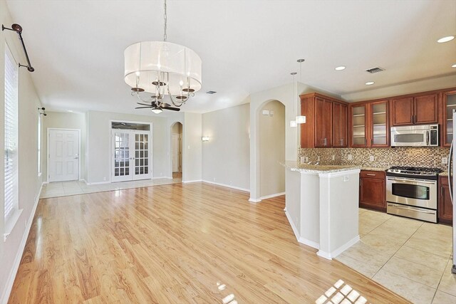 kitchen featuring decorative backsplash, an inviting chandelier, pendant lighting, and appliances with stainless steel finishes