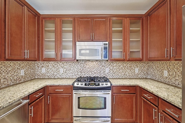 kitchen with tasteful backsplash, light stone counters, and stainless steel appliances