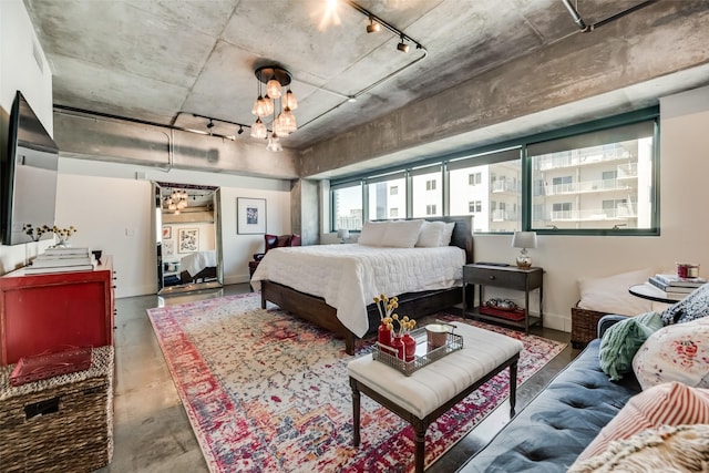 bedroom with concrete flooring, track lighting, and a chandelier