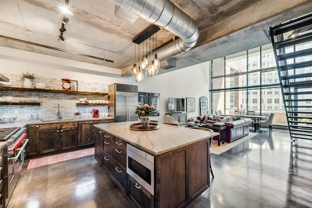 kitchen with floor to ceiling windows, sink, pendant lighting, built in appliances, and a center island