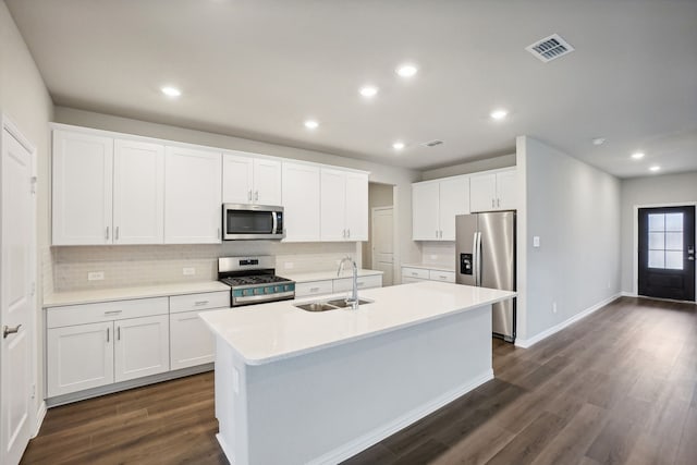 kitchen with white cabinetry, sink, dark wood-type flooring, stainless steel appliances, and a center island with sink