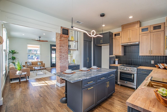 kitchen with hanging light fixtures, high end stainless steel range, light stone countertops, a kitchen island, and light brown cabinets