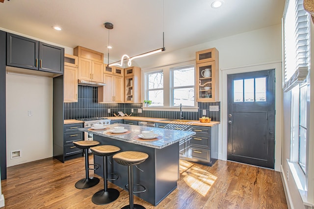 kitchen featuring pendant lighting, sink, a kitchen island, light stone counters, and a kitchen bar