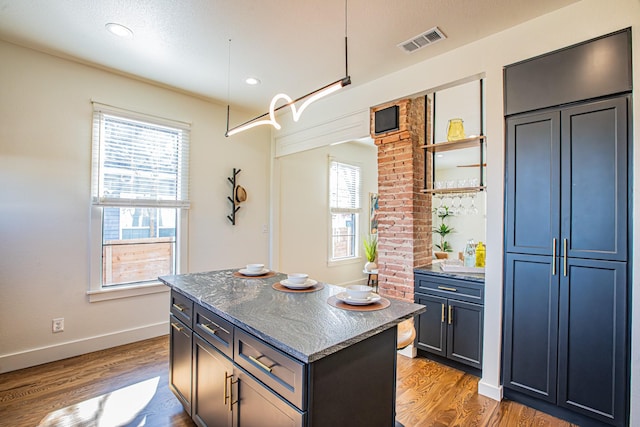 kitchen with a kitchen island, dark stone countertops, and light wood-type flooring