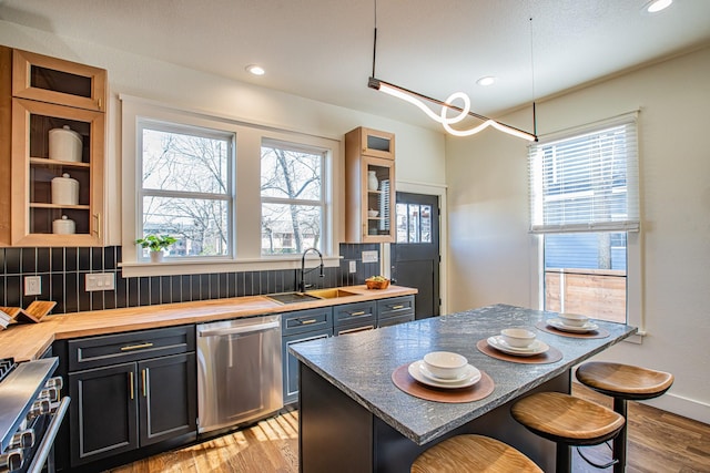 kitchen featuring appliances with stainless steel finishes, sink, backsplash, a kitchen bar, and a center island