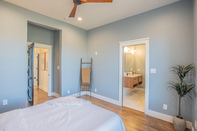 bedroom with ceiling fan, ensuite bathroom, sink, and light hardwood / wood-style floors