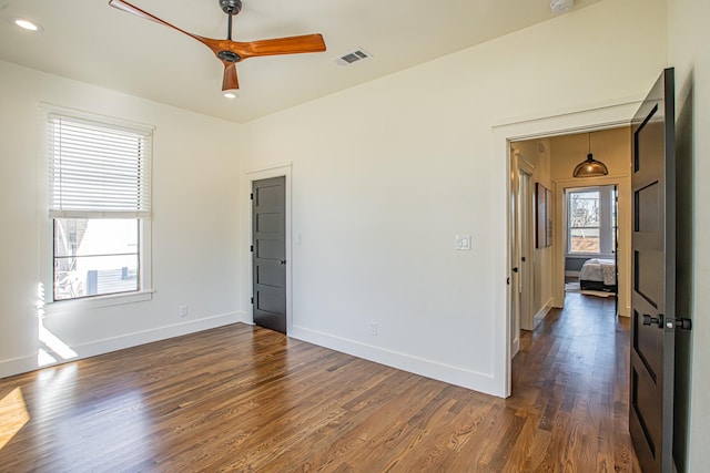 empty room featuring ceiling fan, dark hardwood / wood-style floors, and a wealth of natural light