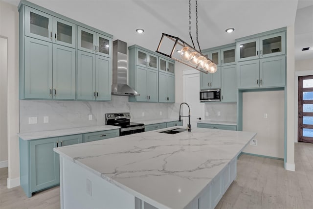 kitchen with pendant lighting, sink, wall chimney exhaust hood, appliances with stainless steel finishes, and light stone counters