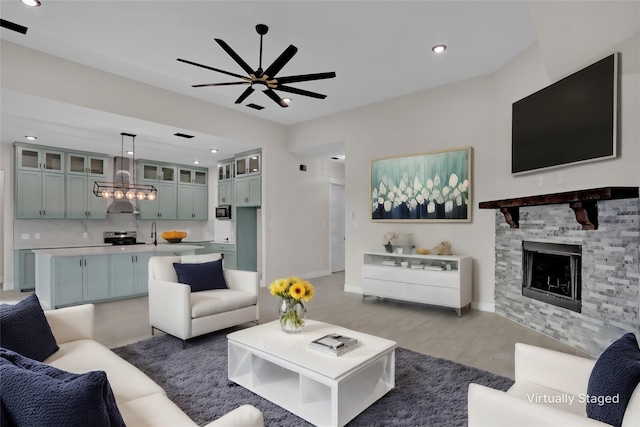 living room with a fireplace, hardwood / wood-style floors, and ceiling fan with notable chandelier