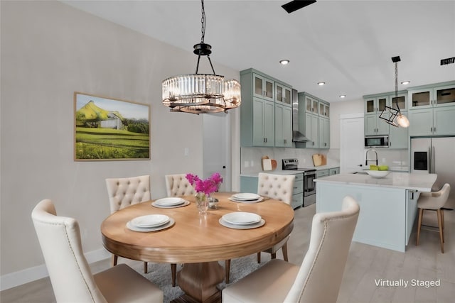 dining space with sink, a chandelier, and light hardwood / wood-style floors