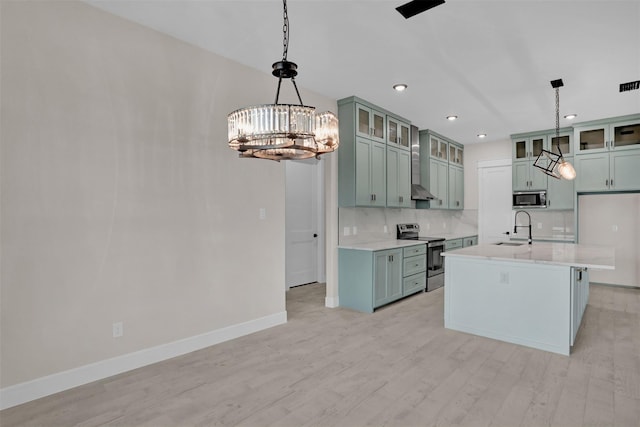 kitchen featuring a kitchen island with sink, sink, light hardwood / wood-style flooring, appliances with stainless steel finishes, and decorative light fixtures