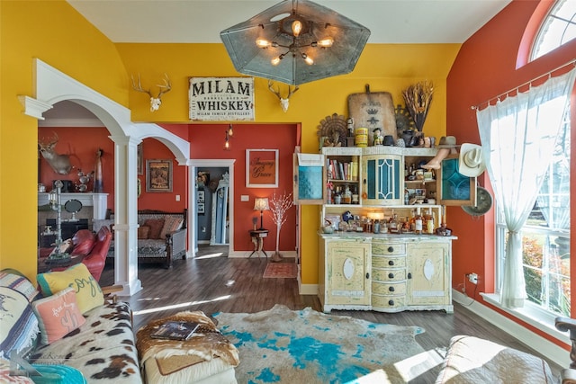 interior space with vaulted ceiling, decorative columns, and dark hardwood / wood-style floors