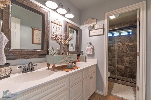 bathroom featuring vanity, tiled shower, tile patterned floors, and toilet