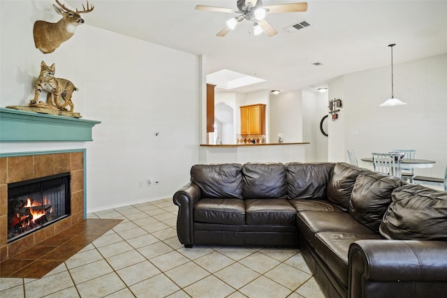 tiled living room featuring a tile fireplace and ceiling fan