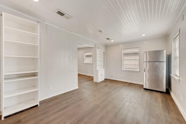 interior space featuring stainless steel fridge, ornamental molding, and hardwood / wood-style floors