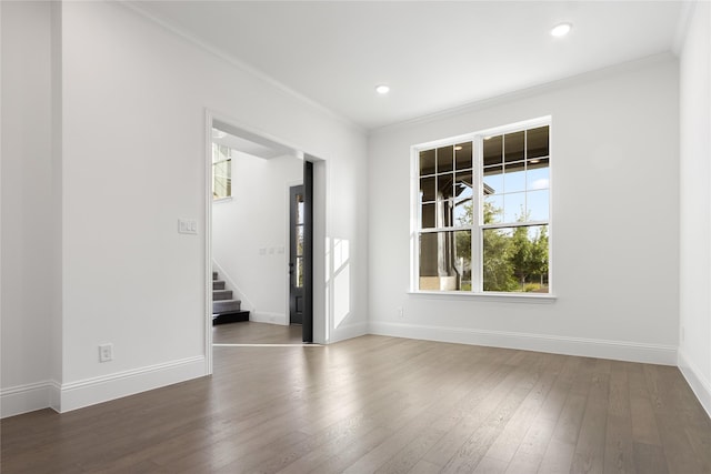 empty room featuring stairs, dark wood-style flooring, baseboards, and crown molding