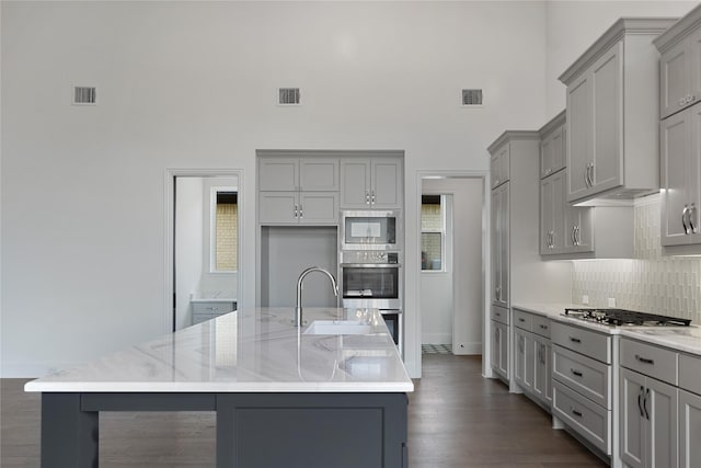 kitchen featuring an island with sink, visible vents, and gray cabinetry