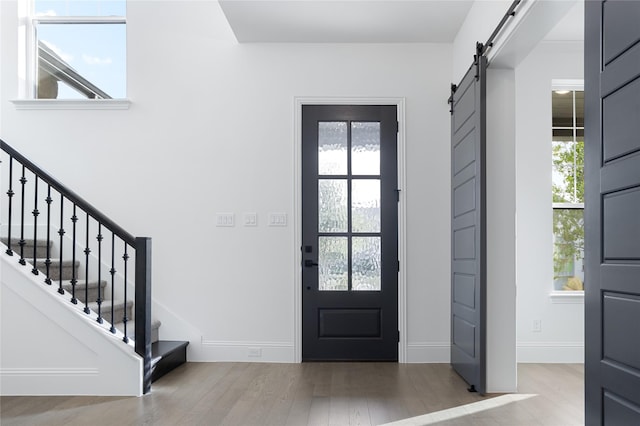 entryway featuring a wealth of natural light, light wood-type flooring, stairway, and a barn door