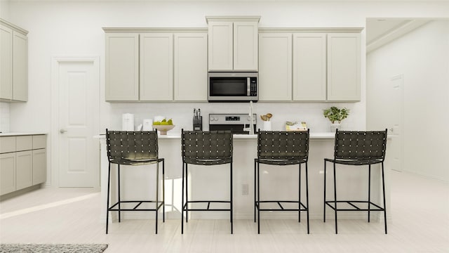 kitchen featuring a kitchen island with sink, decorative backsplash, a breakfast bar area, and stainless steel appliances