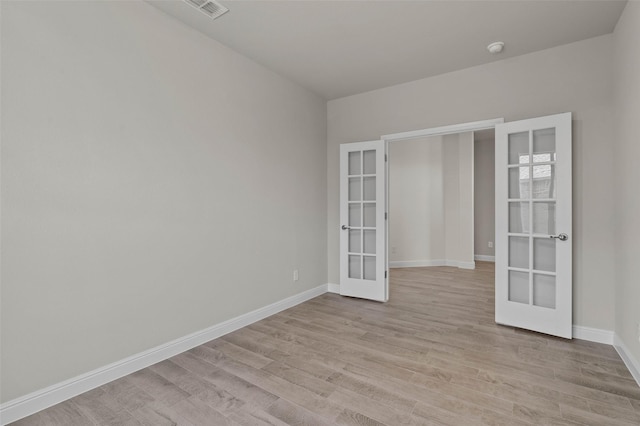 empty room featuring french doors and light hardwood / wood-style flooring