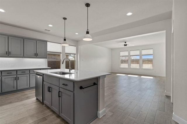 kitchen featuring gray cabinets, ceiling fan, sink, and an island with sink