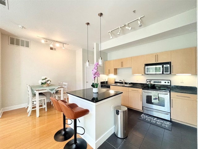 kitchen with sink, pendant lighting, stainless steel electric stove, light brown cabinetry, and a kitchen island