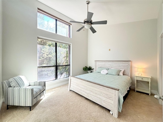 carpeted bedroom with ceiling fan and a high ceiling