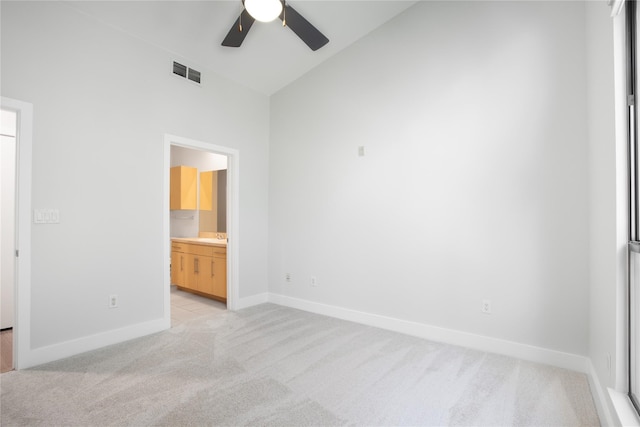 unfurnished bedroom with ensuite bathroom, ceiling fan, and light carpet