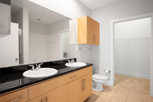 bathroom featuring toilet, vanity, tile patterned floors, and a shower with shower door