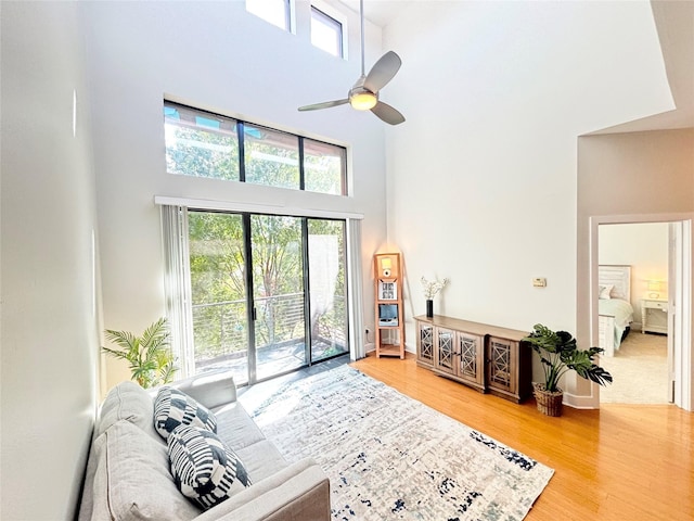 living room featuring a high ceiling, ceiling fan, and wood-type flooring