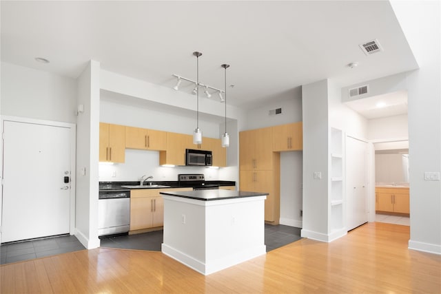 kitchen featuring sink, hanging light fixtures, light brown cabinetry, appliances with stainless steel finishes, and a kitchen island