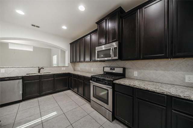 kitchen with tasteful backsplash, sink, light tile patterned flooring, and appliances with stainless steel finishes