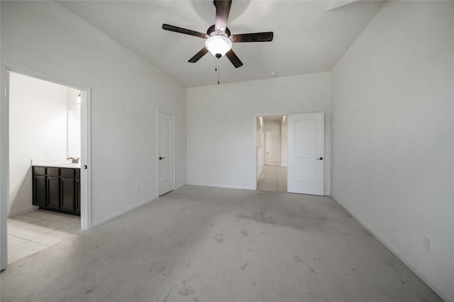 unfurnished bedroom featuring ceiling fan, sink, light colored carpet, and ensuite bath