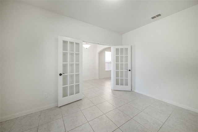 tiled empty room featuring french doors