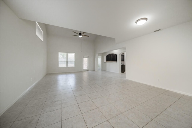 tiled spare room with a towering ceiling and ceiling fan