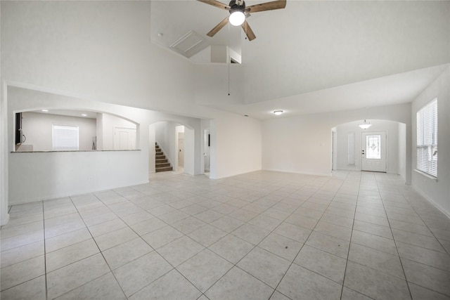 unfurnished living room with a towering ceiling, light tile patterned floors, and ceiling fan