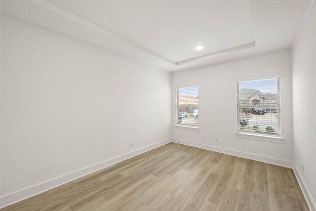 unfurnished room featuring crown molding, a raised ceiling, and light hardwood / wood-style floors