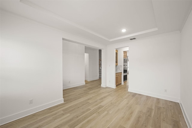 unfurnished room featuring ornamental molding, a tray ceiling, and light wood-type flooring