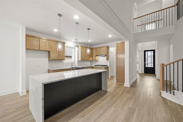 kitchen with hanging light fixtures, a kitchen island, a wealth of natural light, and light hardwood / wood-style flooring